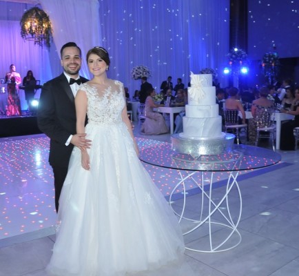 La pareja de enamorados posa para el lente fotográfico de Farah La Revista, junto a su pastel de bodas de estilo amarmolado, elaborado por Nadia Canahuati de Signatures Cakes